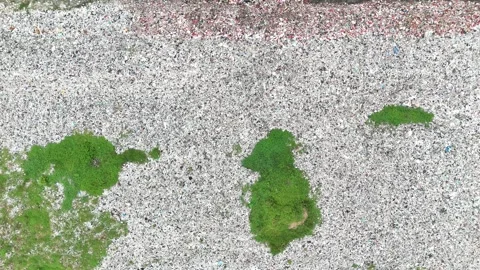 Aerial view of a large pile of trash in a field with green grass. Vidéo 337016142