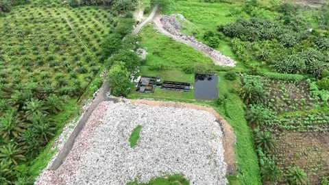 Aerial view of a large pile of trash in a field with green grass. Stock Footage 337016264