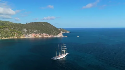 Aerial view of a large sailing ship cruising on the deep blue sea, with the lush Stock Footage 346719880