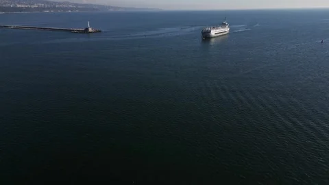 Aerial view of a large ship approaching a coastal lighthouse, calm water and Stock Footage 289201226