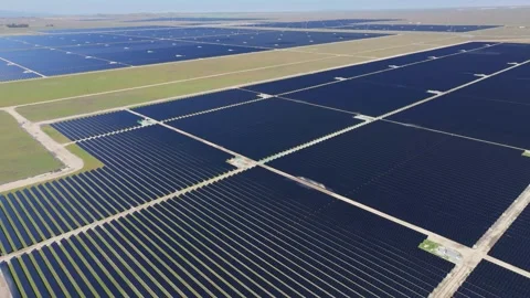 Aerial view of large solar array farm in lush green valley Stock Footage 303044621