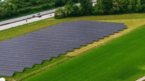 Aerial View of Large Solar Panel Farm Next to Highway Фото