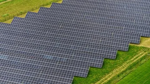 Aerial View of Large Solar Panel Farm in Green Agricultural Field 写真素材