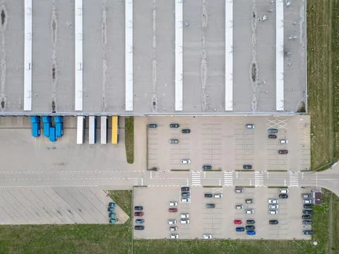 Aerial view of a large warehouse with loading docks, numerous parked cars, .. Stock Photos
