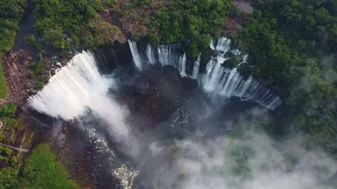 Aerial view of a large waterfall cascading over a cliff with lush green Stock Footage 307891082