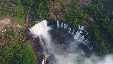 Aerial view of a large waterfall cascading down a cliff surrounded by lush green Stock Footage 307891350