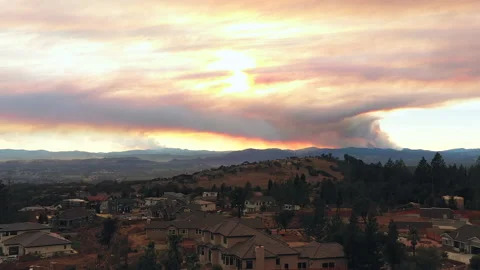 Aerial view of large wildfire and smoke headed towards California city in Stock Footage 137833101