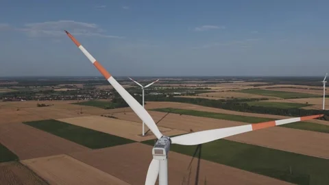 Aerial view of a large wind turbine surrounded by agricultural fields, with Stock Footage 342773101