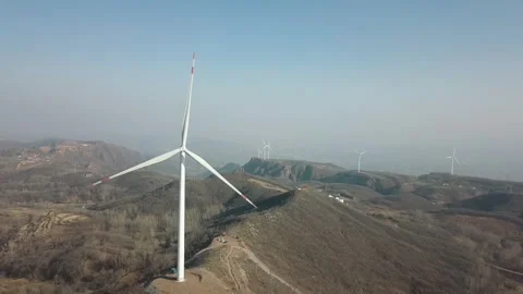 Aerial View of Large Wind Turbines on Rolling Hills Under Clear Blue Sky Stockbeeldmateriaal 334863862