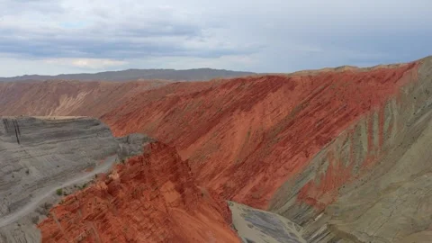 Aerial view of layered red canyon cliffs and mountain road in Xinjiang Stock Footage 345522019