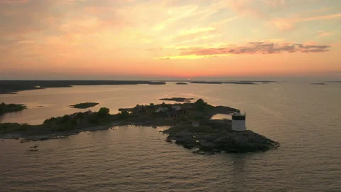 Aerial view of a lighthouse &amp; cabins on a remote island during sunset Stock Footage 134918327