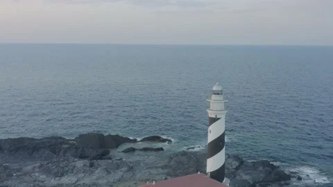 Aerial View Of Lighthouse Standing On The Edge Of A Rocky Cliff Stock Footage 136559893