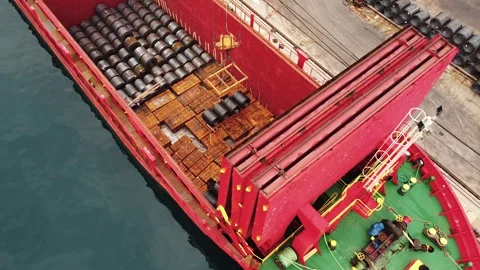 Aerial view of loading a cargo ship in a port. A crane loads metal coils into a Stock Footage 285676095