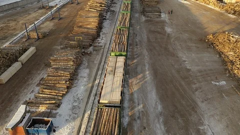 Aerial view of logging train at sawmill hauls stacked wooden logs and tree Stock Footage 127107561