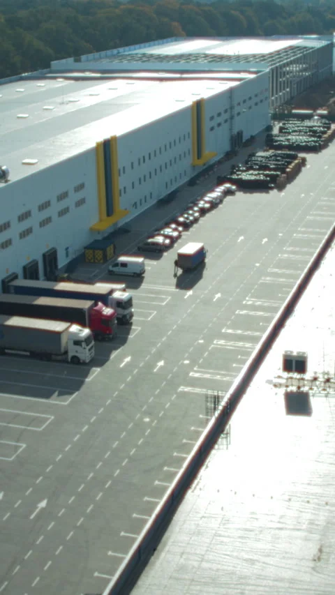 Aerial view of a logistics hub with a large warehouse and parked trucks Stock Footage 328907422