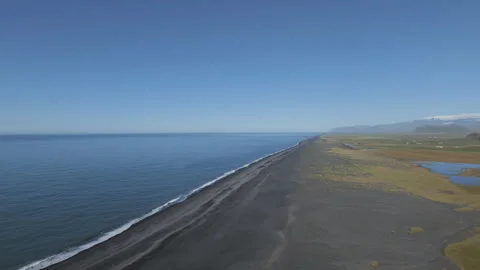 An aerial view of a long, black sand beach next to the blue ocean. Stock Footage 335963596
