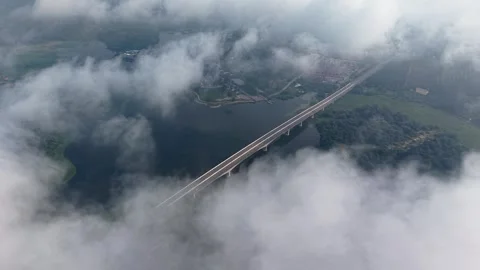 Aerial View of Long Bridge Crossing River Surrounded by Clouds and Forest Stock Footage 339829785