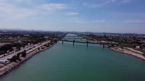 Aerial view of a long bridge over green water canal leading to the city lan.. Stock Footage 337746823