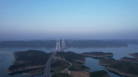 Aerial view of a long cable stayed bridge crossing a large mountain reservoir Stock Footage 342324765
