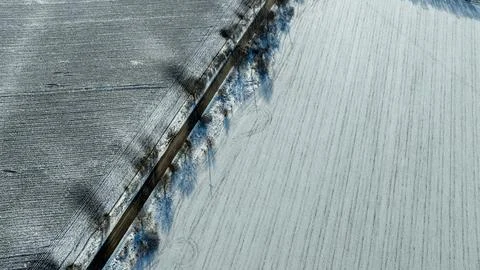 Aerial View of Long Empty Road Through Snowy Winter Fields and Bare Trees. .. Stock Photos