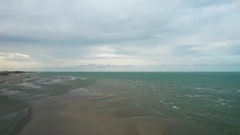 Aerial view of a long, expansive beach with ocean waves and a cloudy sky Stock Footage 331020158