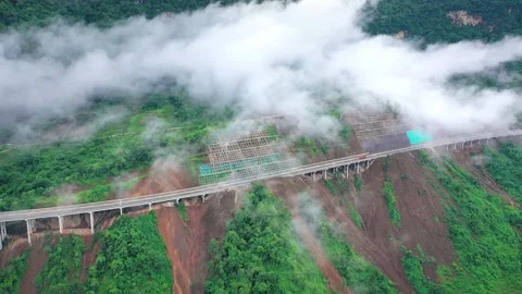 Aerial view of a long highway bridge winding through misty green mountain slopes Video stock 342214666
