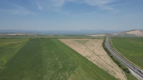 Aerial view of a long highway cutting through green fields and hills. Stock Footage 341274377