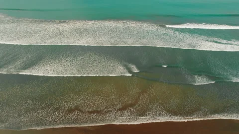 Aerial view of long ocean waves rolling toward the sandy shore in Costa Rica Stock Footage 341366400