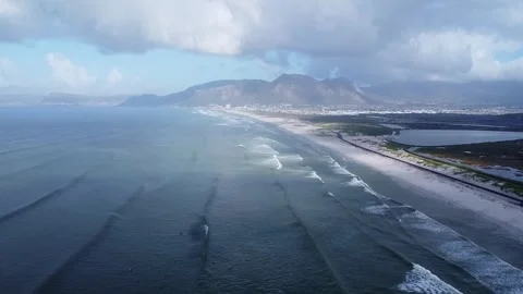 Aerial view of a long sandy beach with waves crashing, mountains in the Stock Footage 308974944