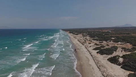 Aerial view of a long sandy coastal beach bordered by turquoise ocean waves and Stock Footage 344142348