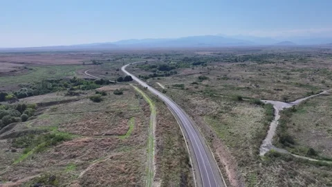Aerial view of long winding road through a vast dry landscape Stock Footage 341883507