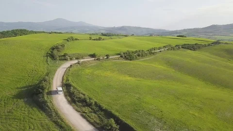Aerial view looking down on a rural road in the Tuscany countryside with a car. Stock Footage 129453580