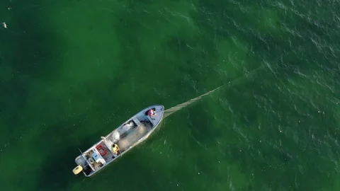 Aerial view looking down on two men pulling in fishing nets as camera rises. Stock Footage 104684703