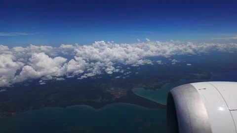Aerial view looking out a plane window showcasing a jet engine over scattered Stock Footage 346124209
