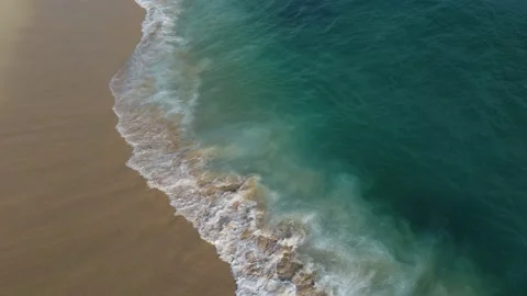 Aerial view looking straight down onto crashing waves hitting a golden beach Vidéo 229785569