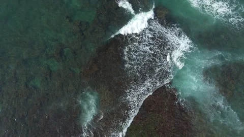 Aerial view looking straight down onto crashing waves hitting a golden beach Vidéo 229916413