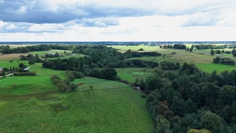 Aerial View of Lush Countryside Fields and Forest Under Dramatic Cloudy Sky Stock Footage 346799321