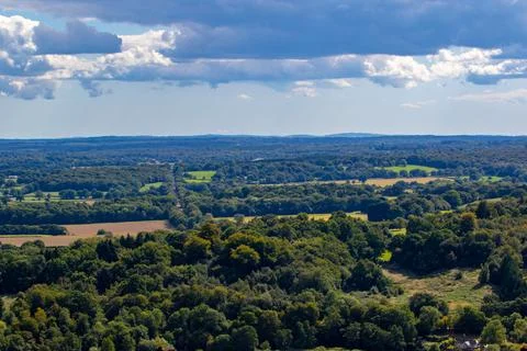Aerial view of a lush countryside with patchwork fields under a cloudy sky. 스톡 사진