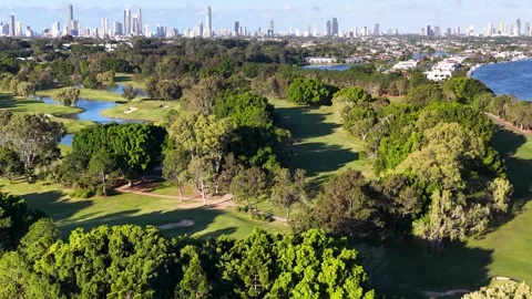 Aerial View of Lush Golf Course and Distant City Skyline 動画素材 339404752