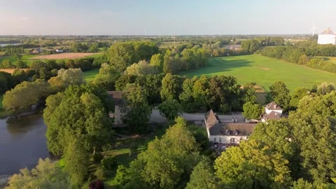 Aerial view of lush green fields, a river, and an industrial plant with tall Vidéo 316374237
