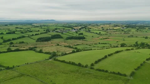 Aerial view of lush green fields. Clouds drift above rolling hills and 스톡 동영상 346087318