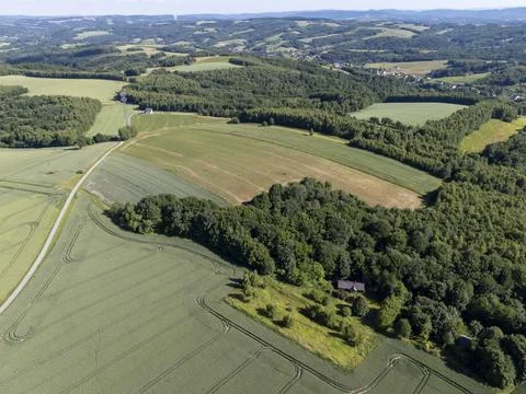 Aerial view of lush green fields and forests under a clear blue sky Stock Photos