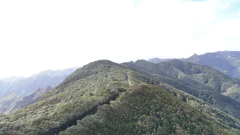 Aerial view of lush green mountain landscape showcasing rocky cliffs and dense Видео 335877367