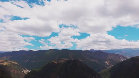 Aerial View of Lush Mountain Range Under Cloudy Blue Sky Stock-Footage 334829281