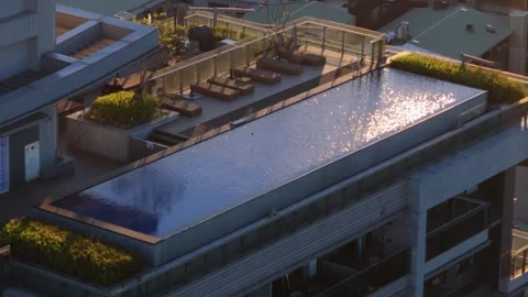 Aerial View of Luxurious Rooftop Infinity Pool with Birds Playing at Sunset 스톡 동영상 314120920