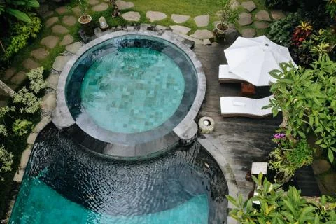 Aerial view of luxury round pool with white umbrellas and sun beds in tropica Stockfoto's