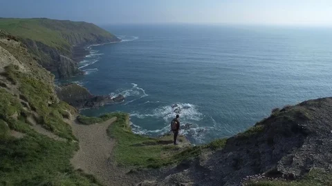 Aerial view of man with backpack on top of a cliff, Ireland Stock Footage 84271105