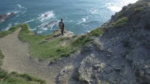 Aerial view of man with backpack on top of a cliff - Ireland Stock Footage 84271115