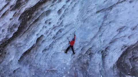 Aerial view of a man climbing a massive frozen waterfall Stock Footage 320519556