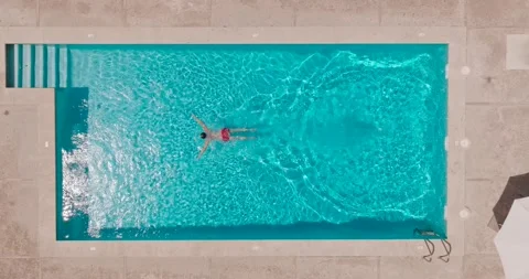 Aerial view as a man dives into the pool and swims Stock Footage 232734863